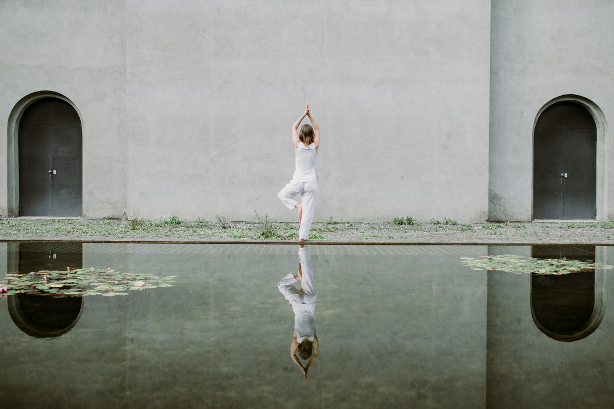 Yoga by a reflecting pool between whitewashed arches
