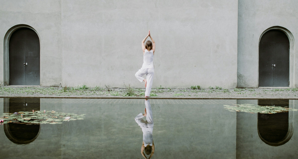 Yoga by a reflecting pool between whitewashed arches